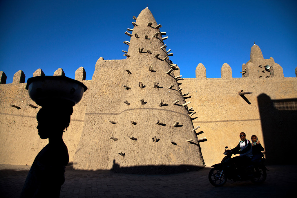 Residents of Timbuktu pass by Djingareyber Mosque, among the historical architectural structures that earned the city the designation of a UNESCO World Heritage Site. Residents of Timbuktu pass by Djingareyber Mosque, among the historical architectural structures that earned the city the designation of a UNESCO World Heritage Site.
