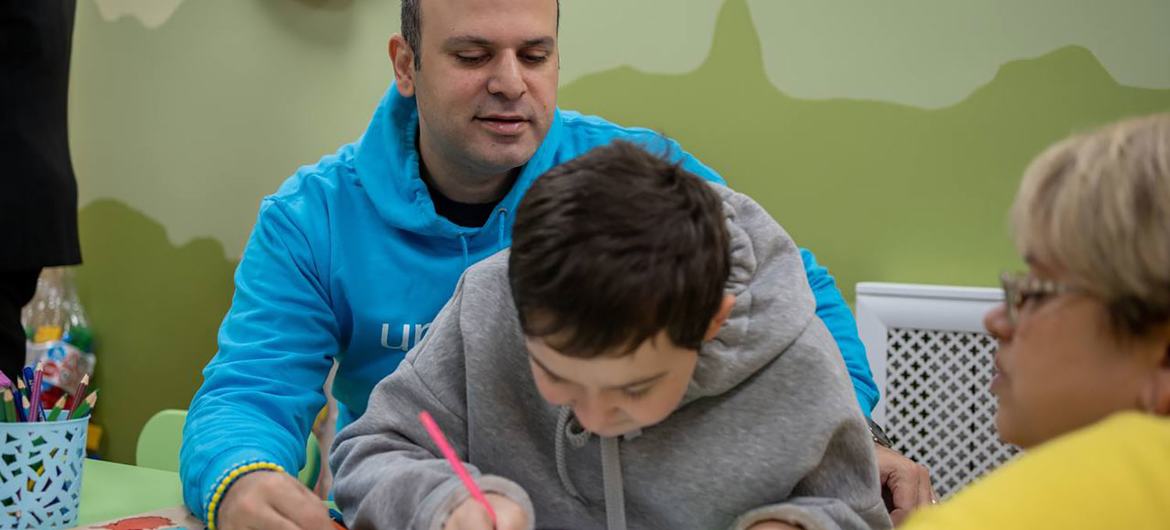 Munir Mammadzade sits with a young Ukrainian in a UNICEF-supported facility. Munir Mammadzade sits with a young Ukrainian in a UNICEF-supported facility.