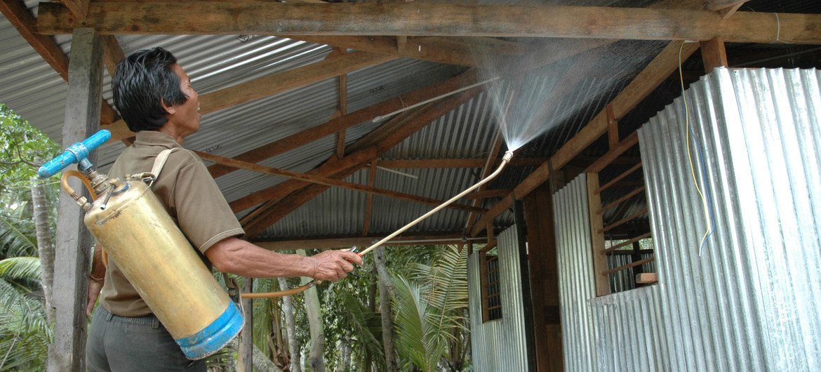 A worker sprays insecticide on the surfaces of a shelter to control the spread of mosquitoes and mitigate the risk of malaria. A worker sprays insecticide on the surfaces of a shelter to control the spread of mosquitoes and mitigate the risk of malaria.