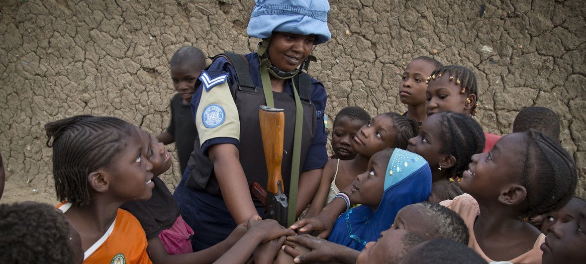 A Rwandan peacekeeper from the MINUSMA Formed Police Unit speaks with children while patrolling the streets of Gao in northern Mali. A Rwandan peacekeeper from the MINUSMA Formed Police Unit speaks with children while patrolling the streets of Gao in northern Mali.